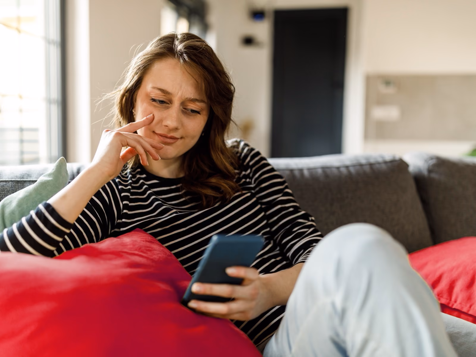 Kvinne som slapper av i sofaen med mobiltelefonen