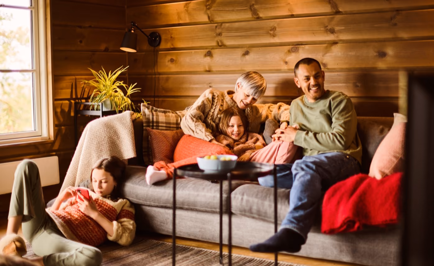 Familie som koser seg sammen i sofaen på hytta