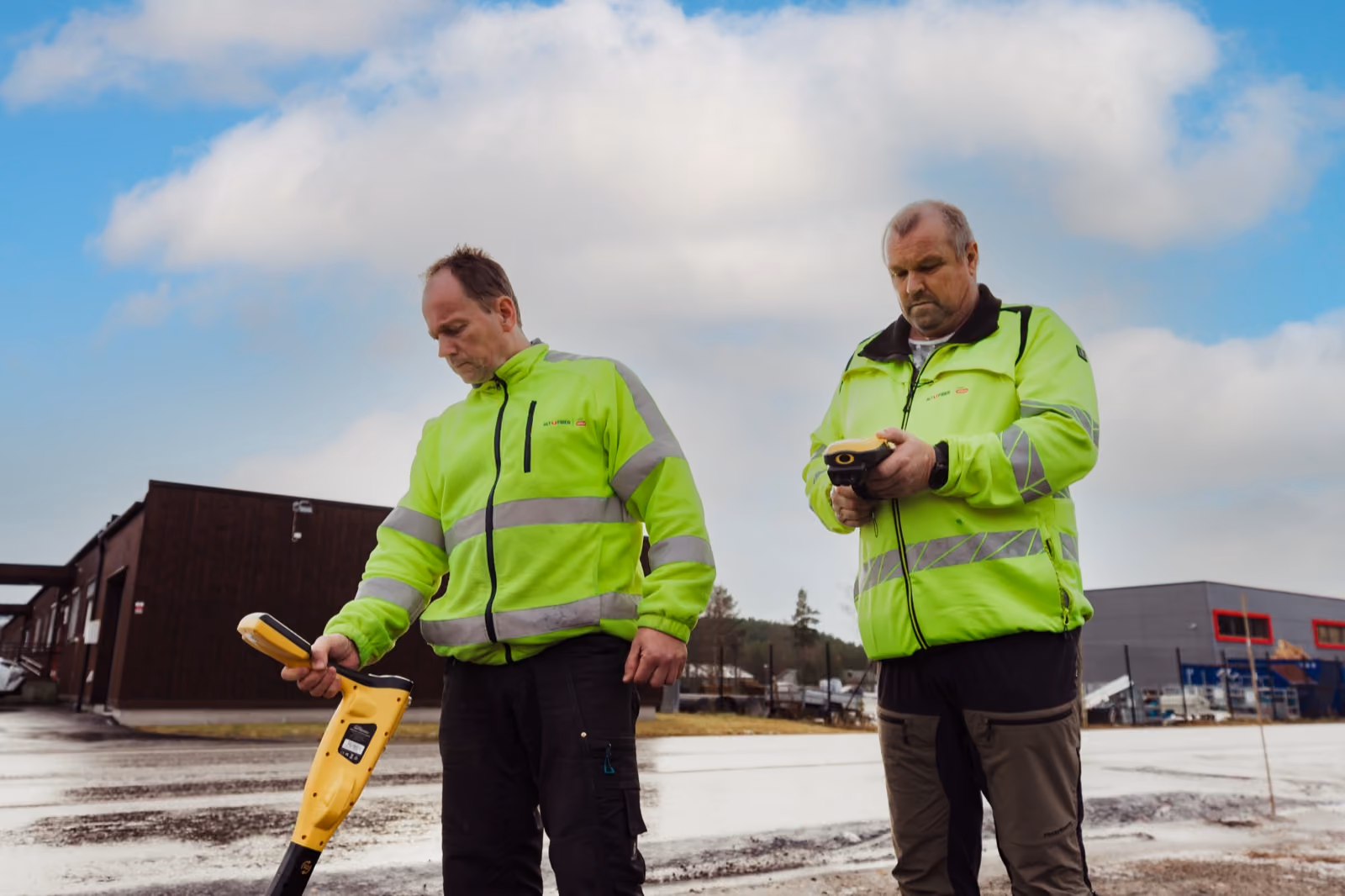 Altifiber-montør i refleksjakke med kabelsøker ute i felt