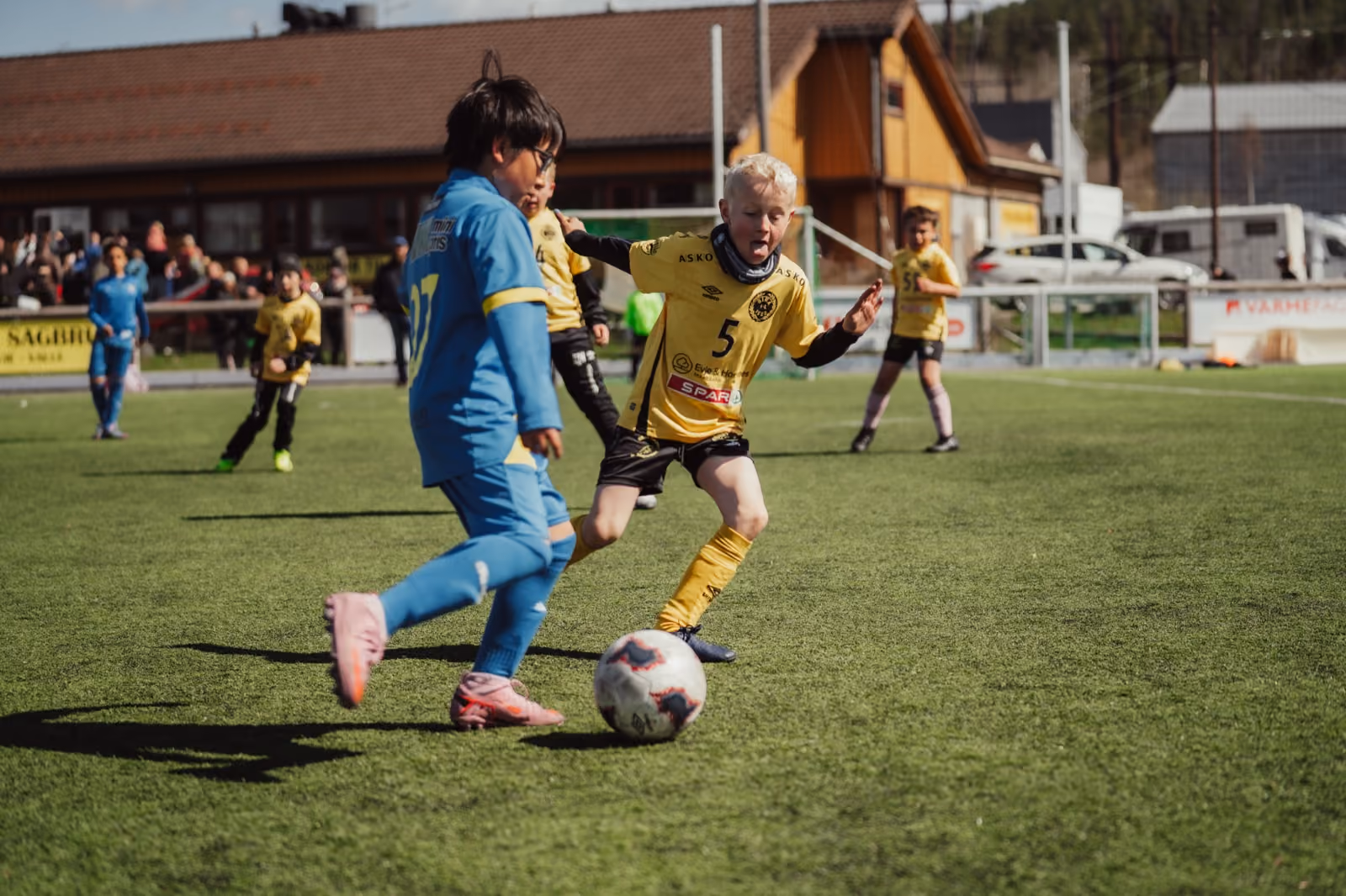 Barn spiller fotball på en lokal kunstgressbane