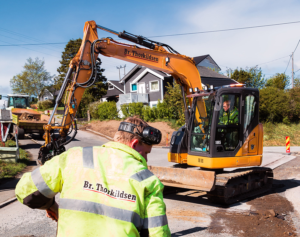 To menn utenfor et bygg med en trommel med oransje fiberkabel