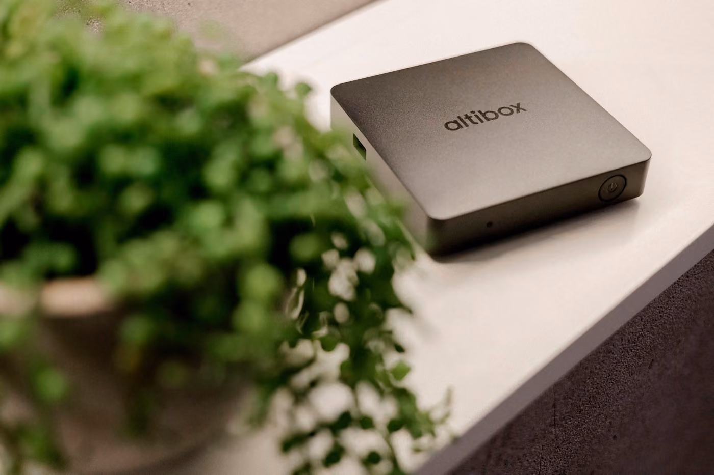 Altibox TV-dekoder på en benk ved en grønn plante