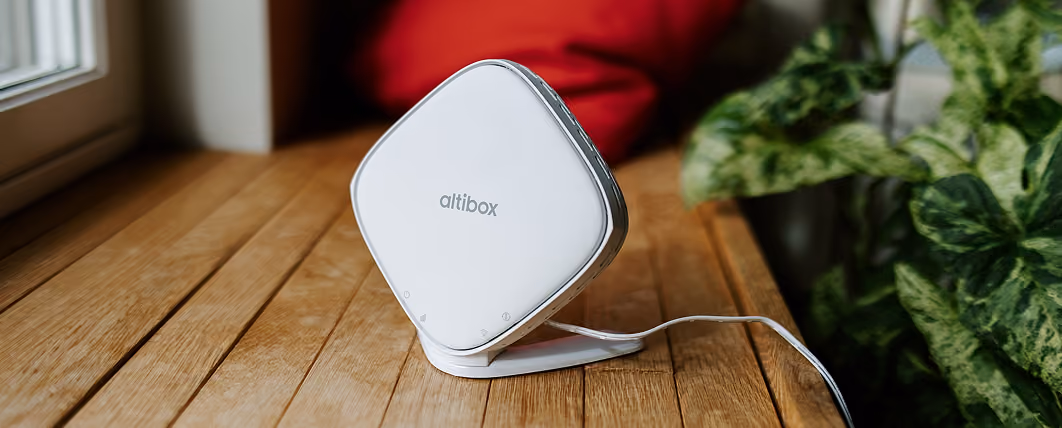 Altibox Wifi-enhet på et tregulv ved et vindu