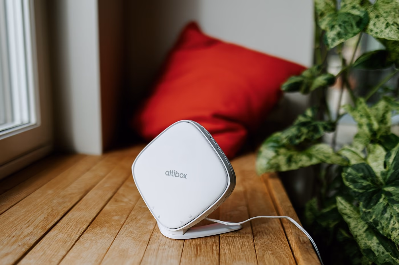 Altibox Wifi-enhet på et tregulv ved et vindu