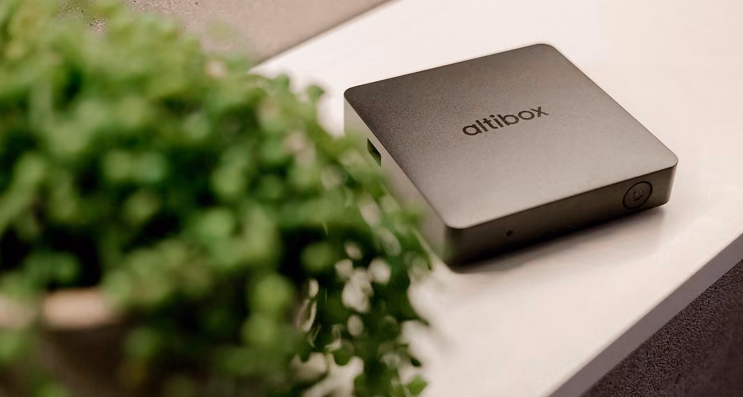 Altibox TV-dekoder på en benk ved en grønn plante