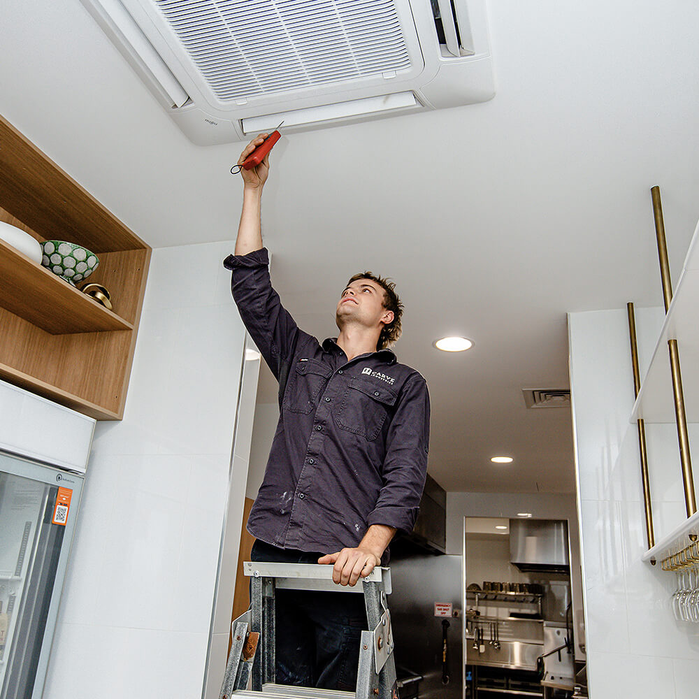Carve team member measures air-conditioning output in commercial kitchen