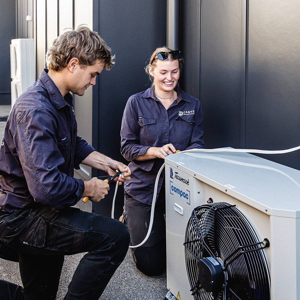 Team members smiling while installing air-conditioning unit
