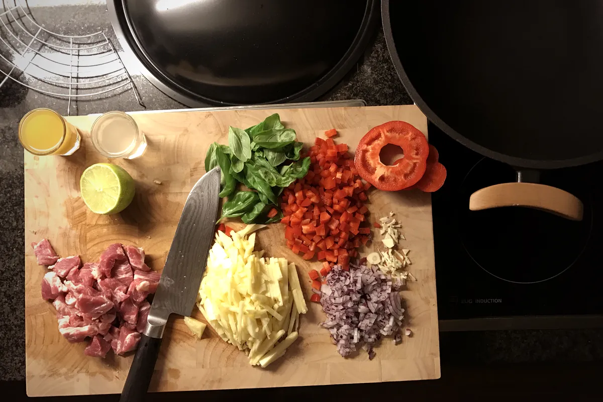 Mise en place auf dem Schneidebrett: Fleisch, Gemüse und Kräuter vor dem Kochen