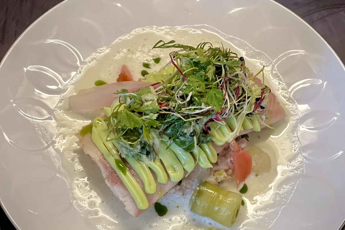Angerichteter Fischgang mit Kräutersalat und Erbsen