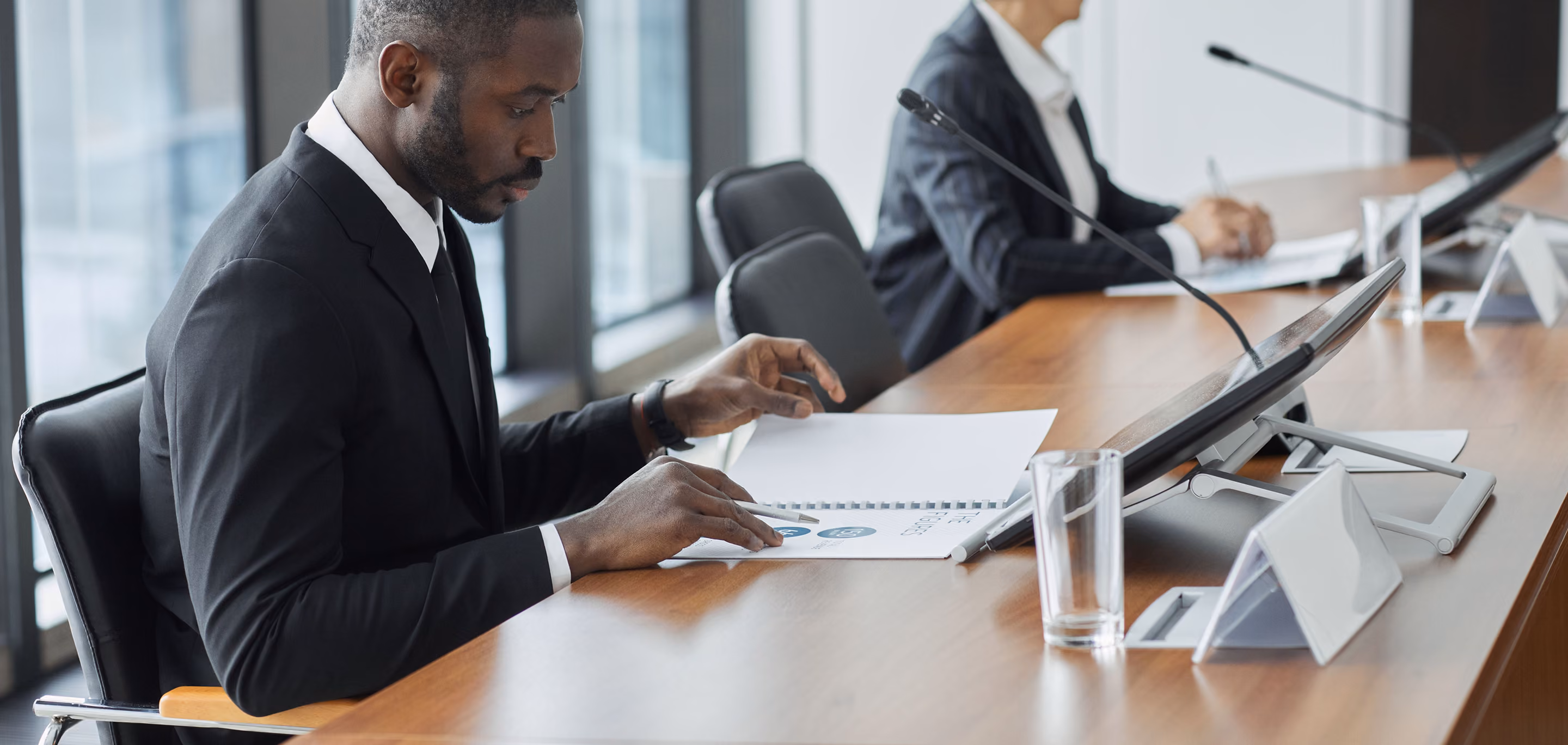 Business professionals reviewing policy reports and documents during a strategic corporate meeting in a conference room.