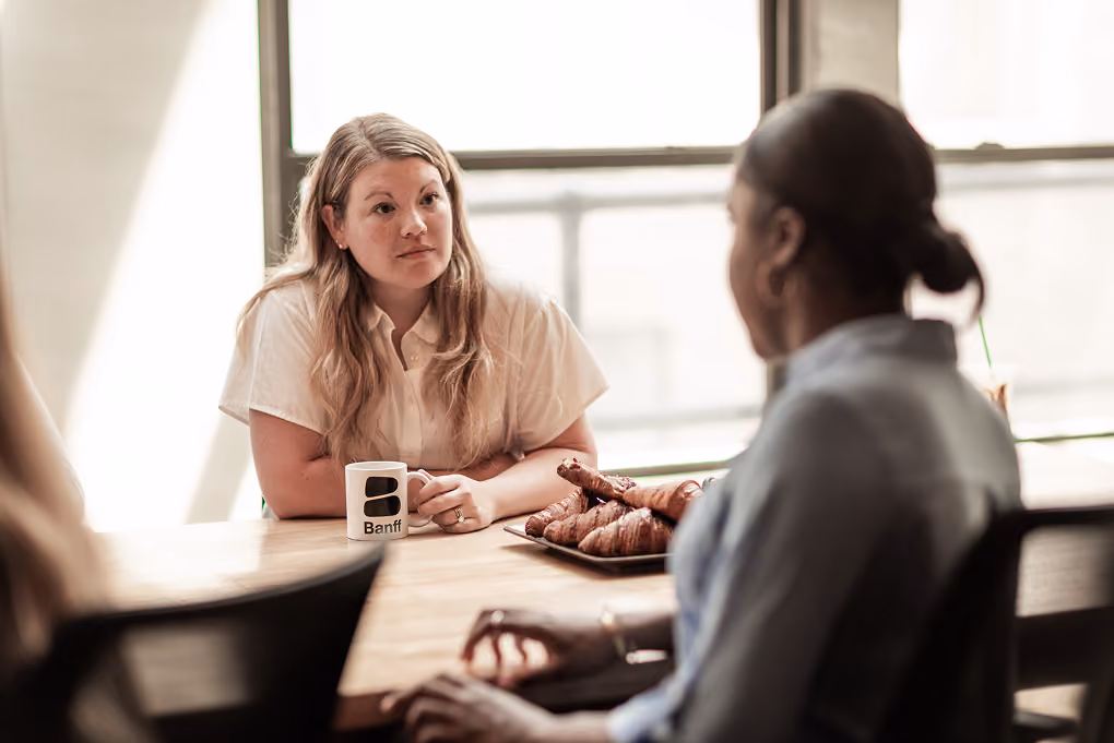 Two Banff advisors in conversation over coffee at a meeting table