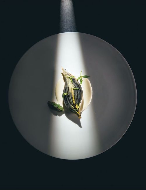 Modern plate with black tuile, avocado and edible pansies