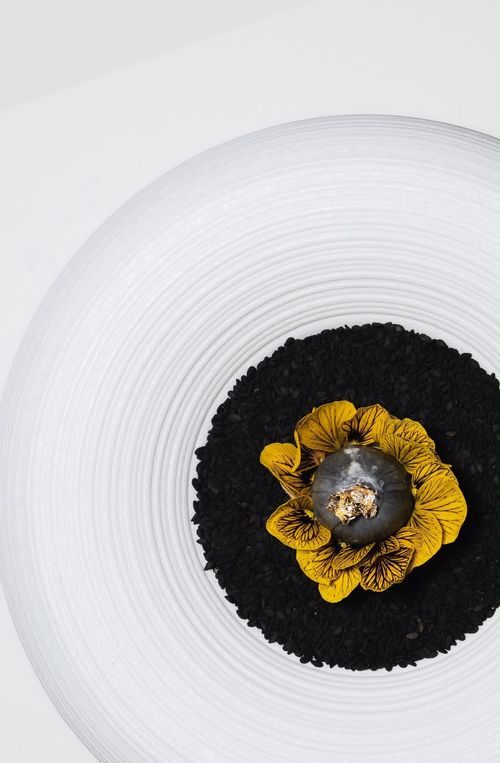 A single composed dish with gold leaf and pansy petals