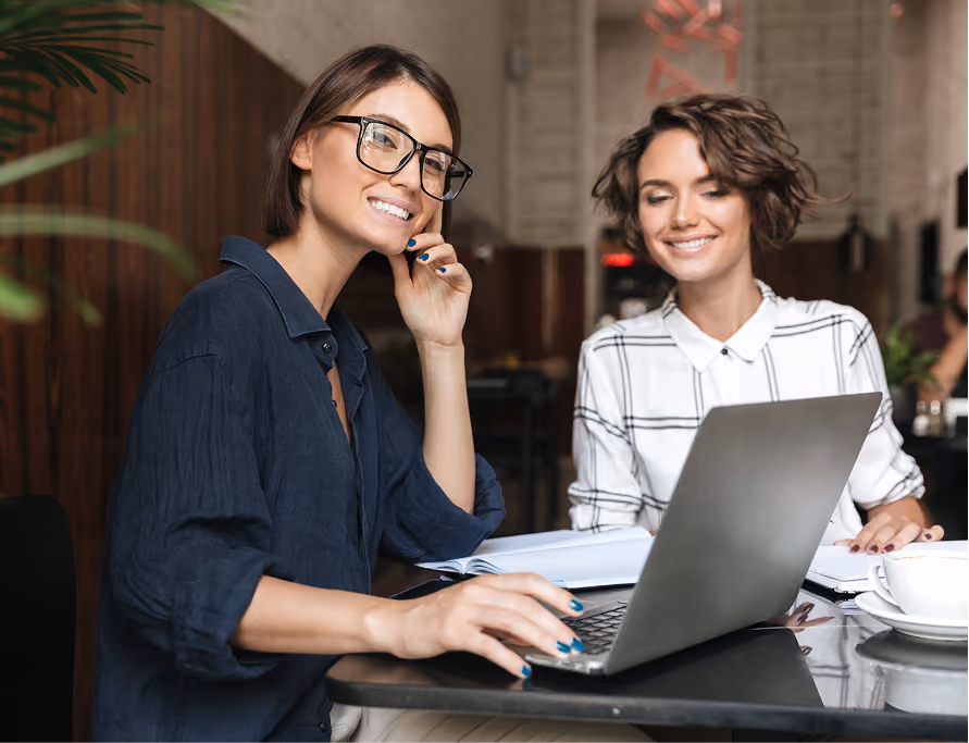 Zwei Frauen am Laptop bei der gemeinsamen Jobsuche.