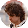 Person with curly hair looking downward against a blurred white background.