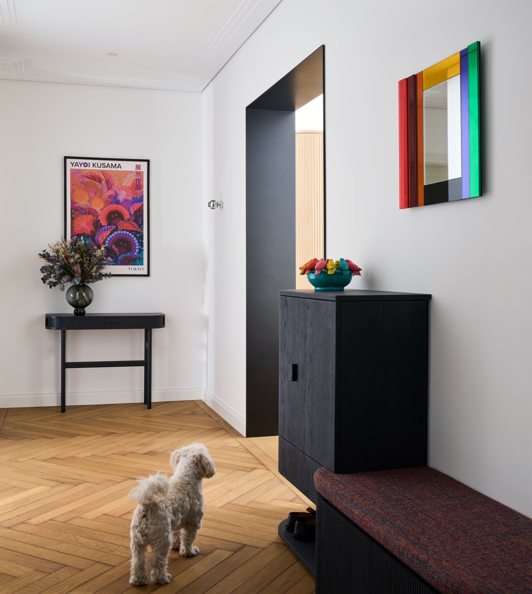 Innenarchitektur-Projekt: Flur mit Fischgrätparkett, Yayoi-Kusama-Poster, schwarzer Konsole und farbigem Spiegel