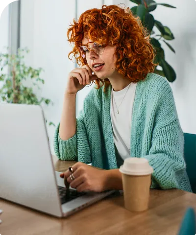 A person is sitting, focused on a laptop screen.