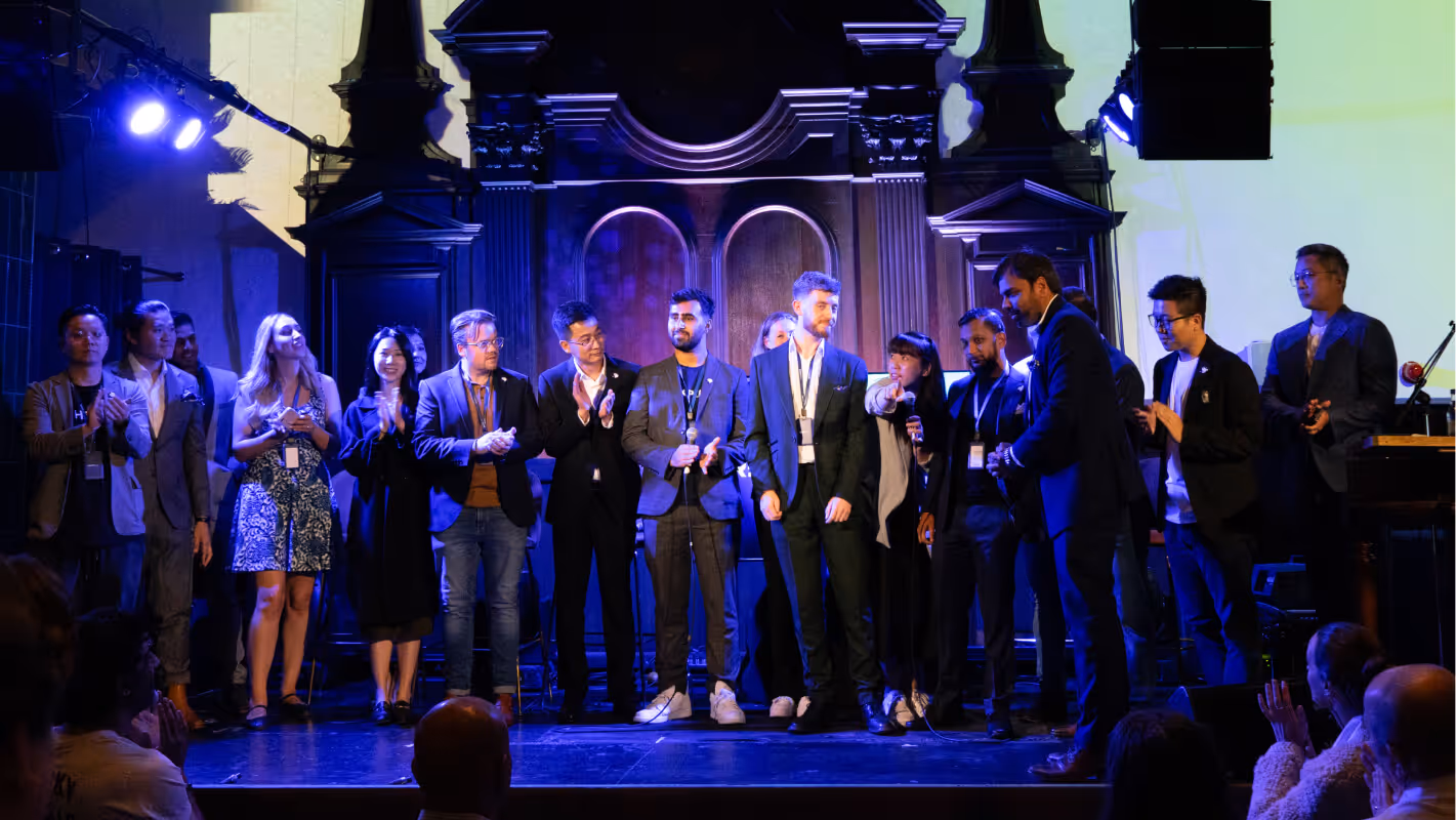 A group of people standing on stage with a microphone, delivering a presentation or engaging in a public speaking event.