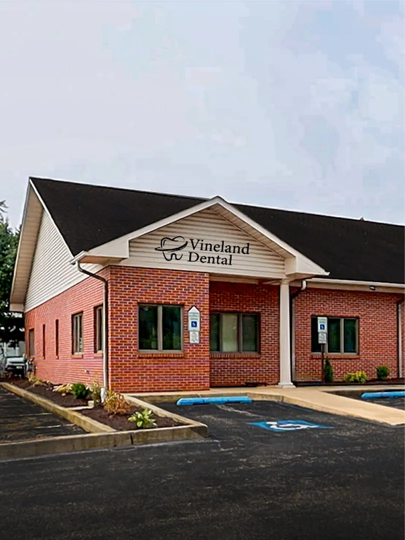 Brick dental office building with Vineland Dental logo and handicap parking spaces at front.