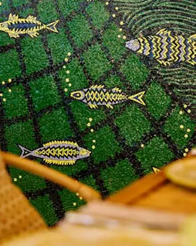 Mosaic floor with yellow and black fish designs swimming on a green checkered background with black grid lines.