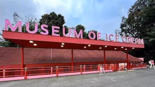 Outdoor view of Museum of Ice Cream over a red structure with people nearby under a blue sky.