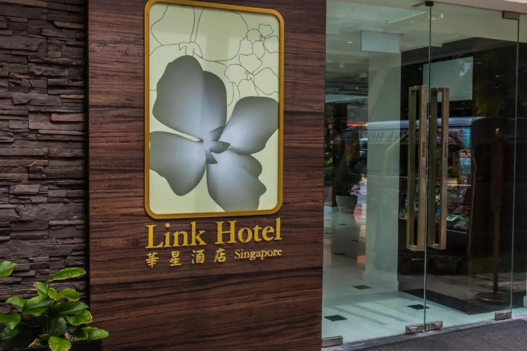 Glass entrance doors to Link Hotel with floral logo and wood-paneled wall background.