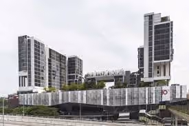 Outdoor view of The Tennery showcasing its modern multi-story building complex with glass and metal facades under a cloudy sky.