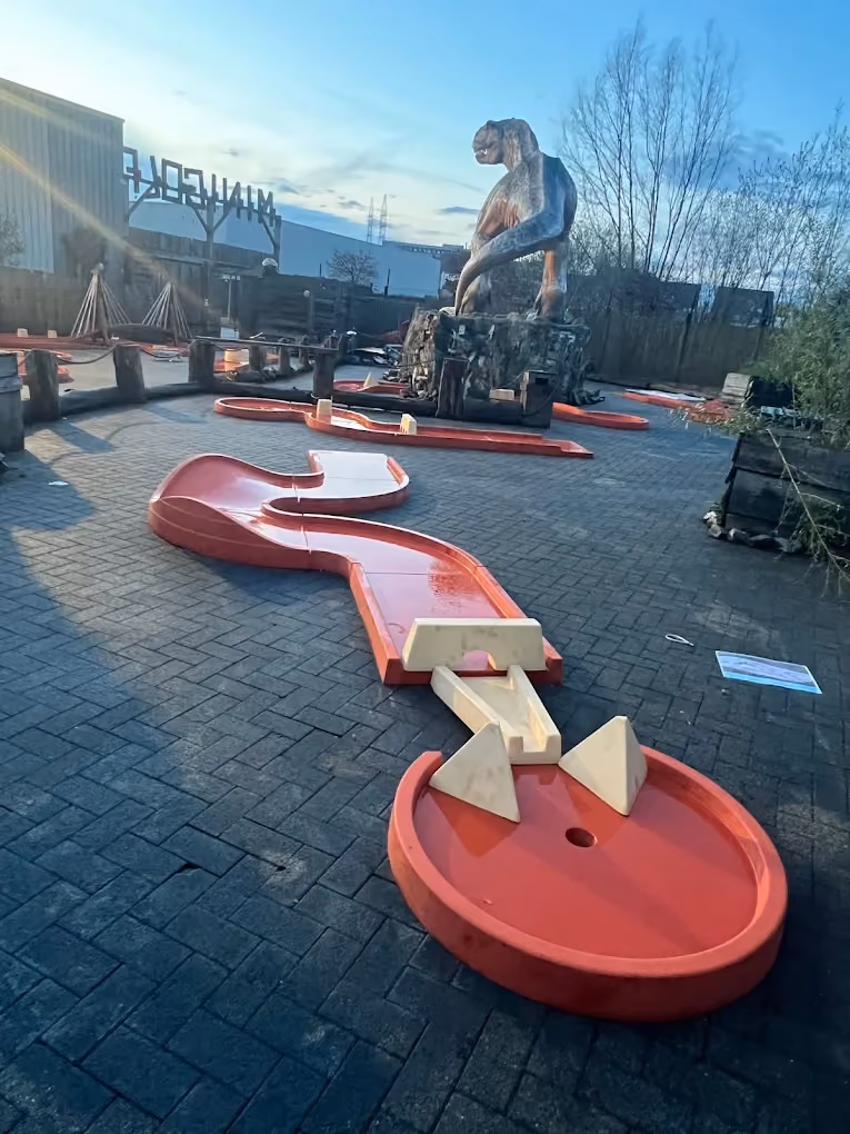 Piste de mini golf à obstacles devant un dinosaure