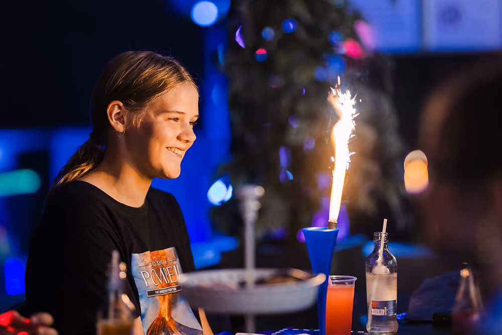 Adolescente souriante devant un dessert avec cierge magique