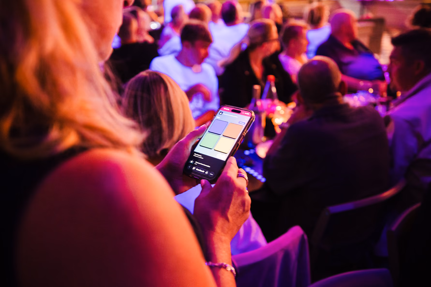 Participante tenant son smartphone lors d'une soirée