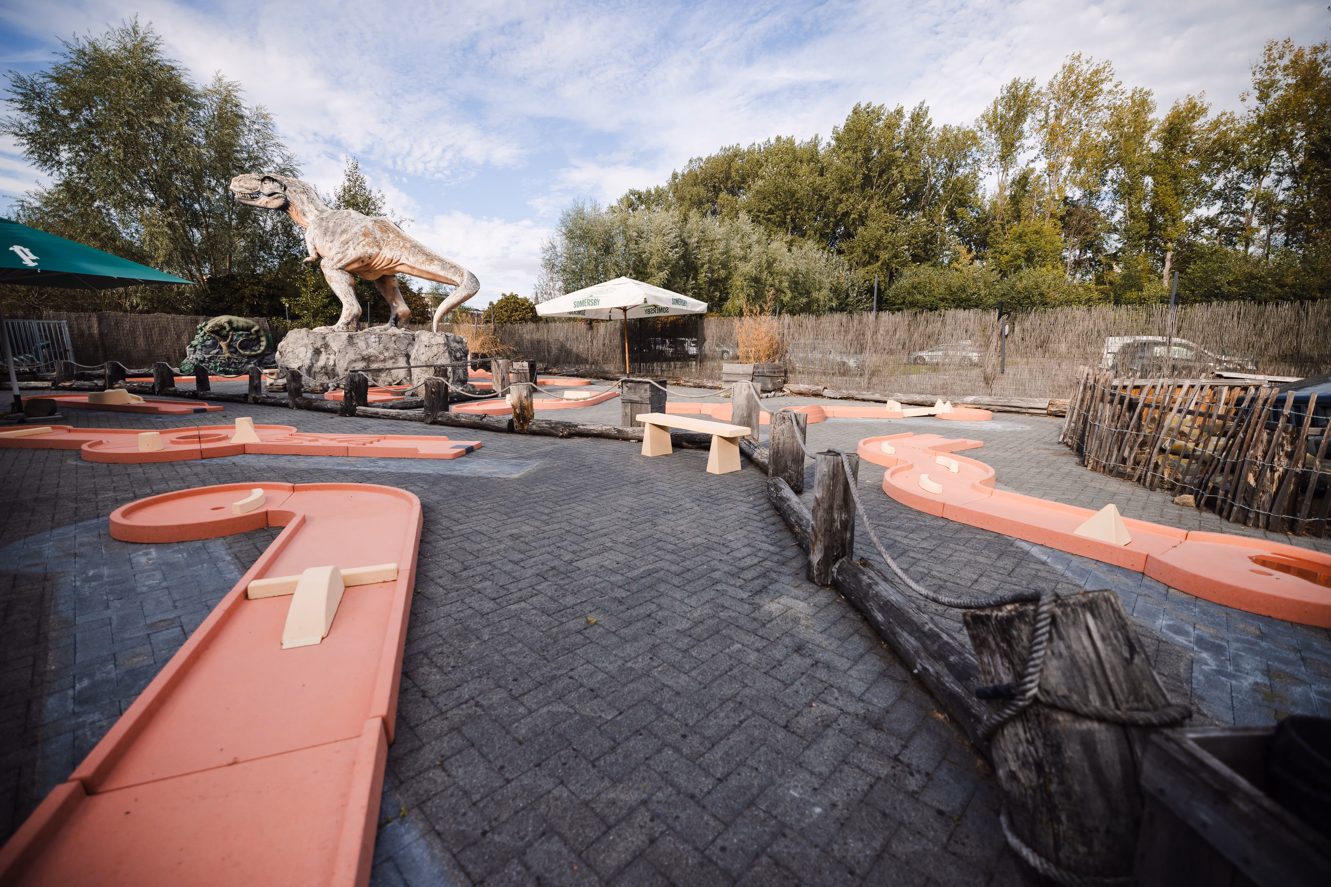 Pistes du mini golf extérieur avec un dinosaure en arrière-plan