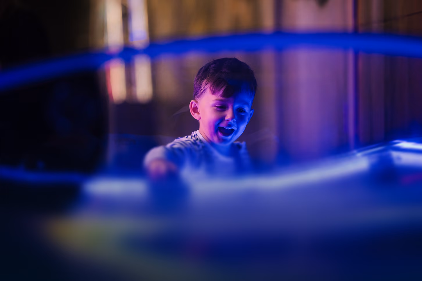 Enfant souriant dans la salle d'arcade éclairée au néon