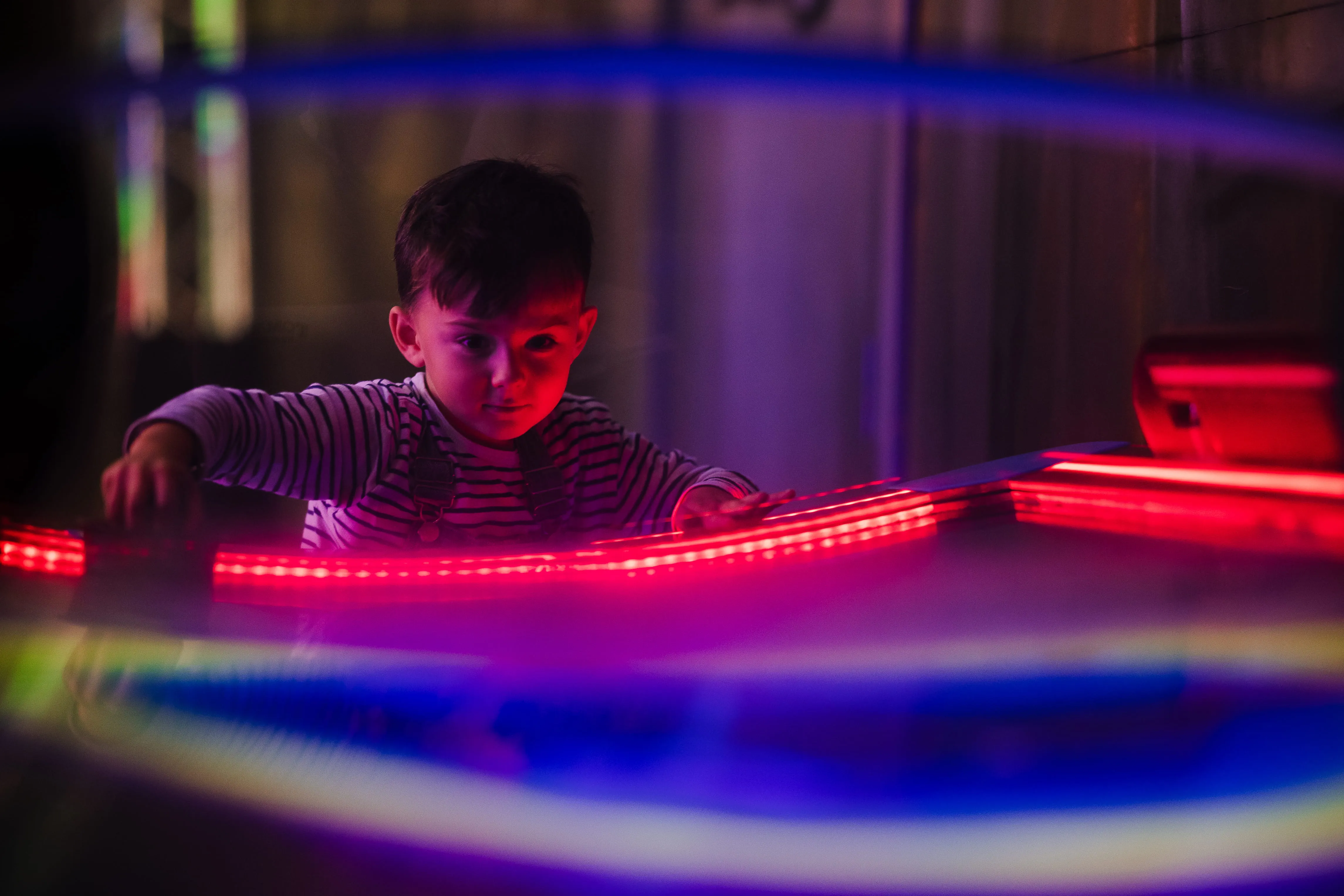 Enfant jouant à un jeu d'arcade éclairé au néon
