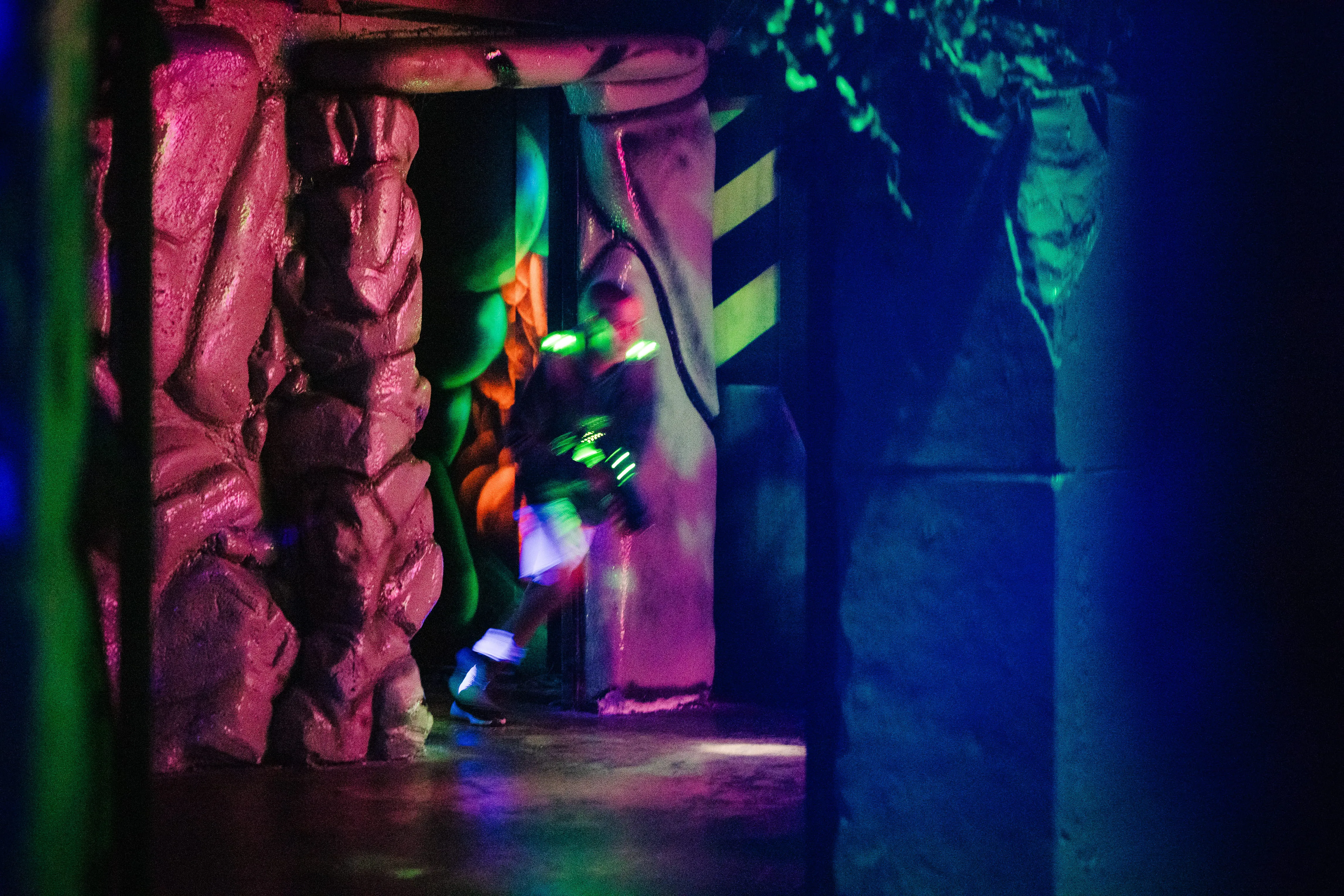 Joueur dans un couloir aux parois de roche d'une arène de laser game