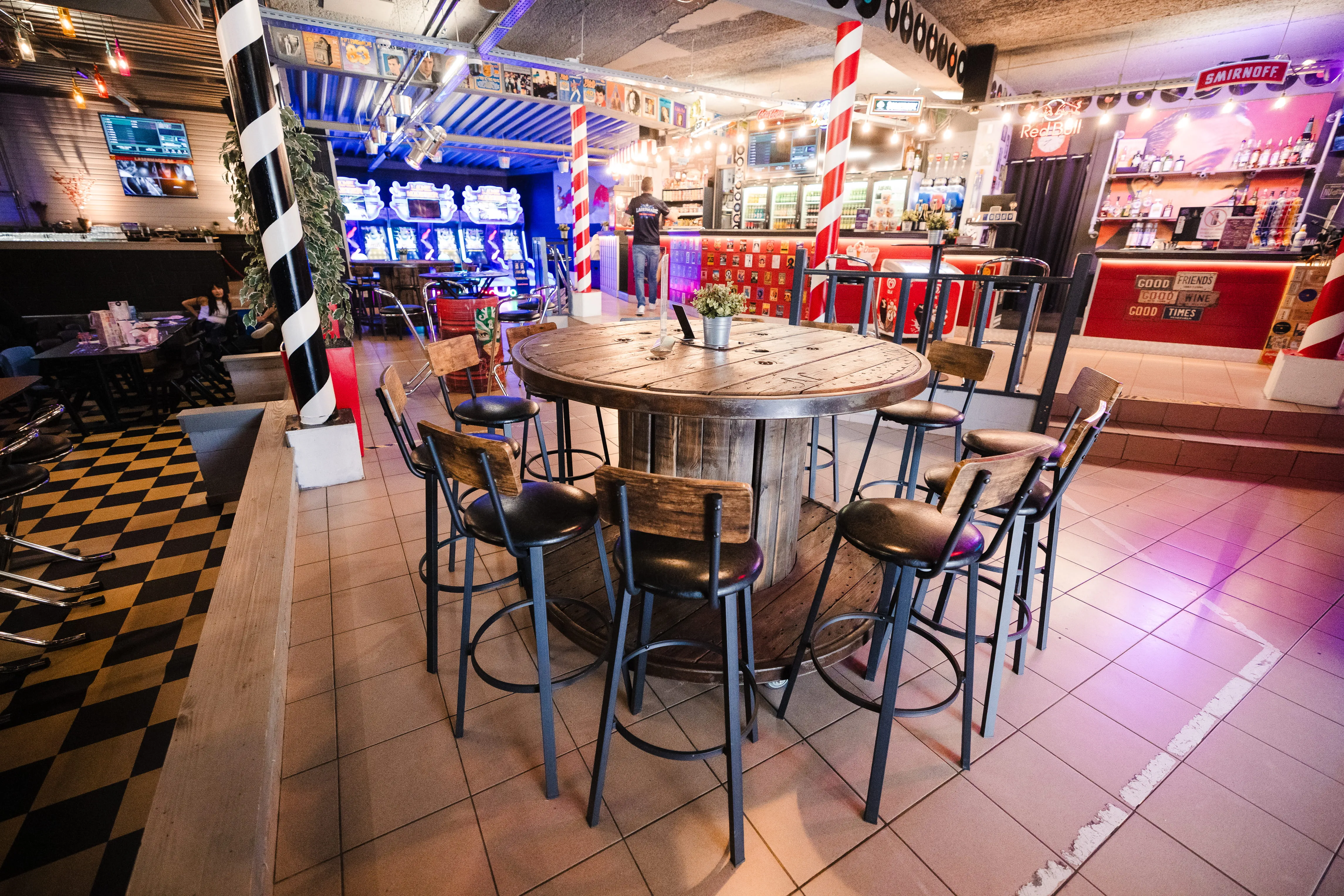 Espace bar et tables hautes sur sol en damier, colonnes rayées rouge et blanc