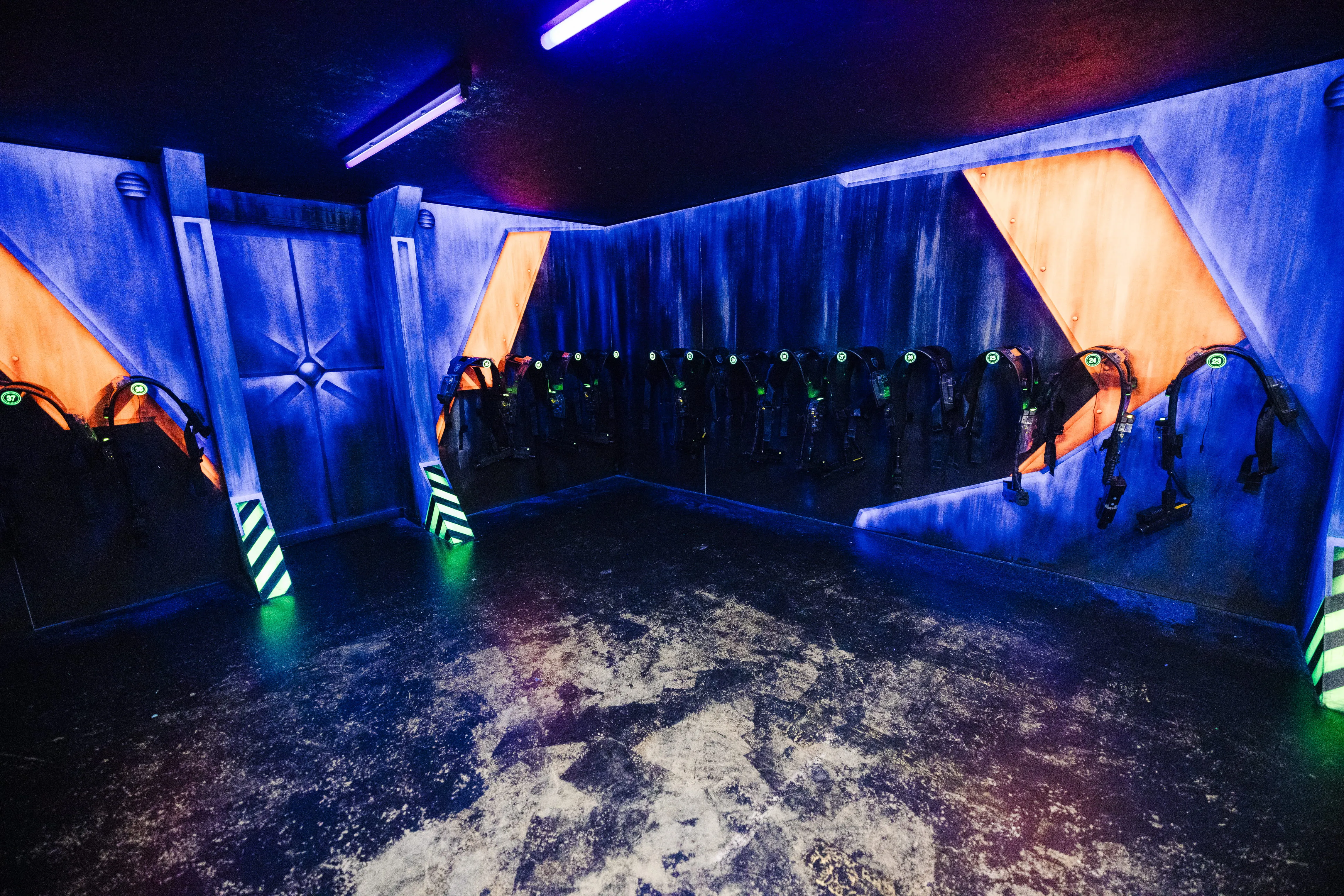 Salle d'équipement de Laser Magic, gilets de laser game alignés sous éclairage bleu