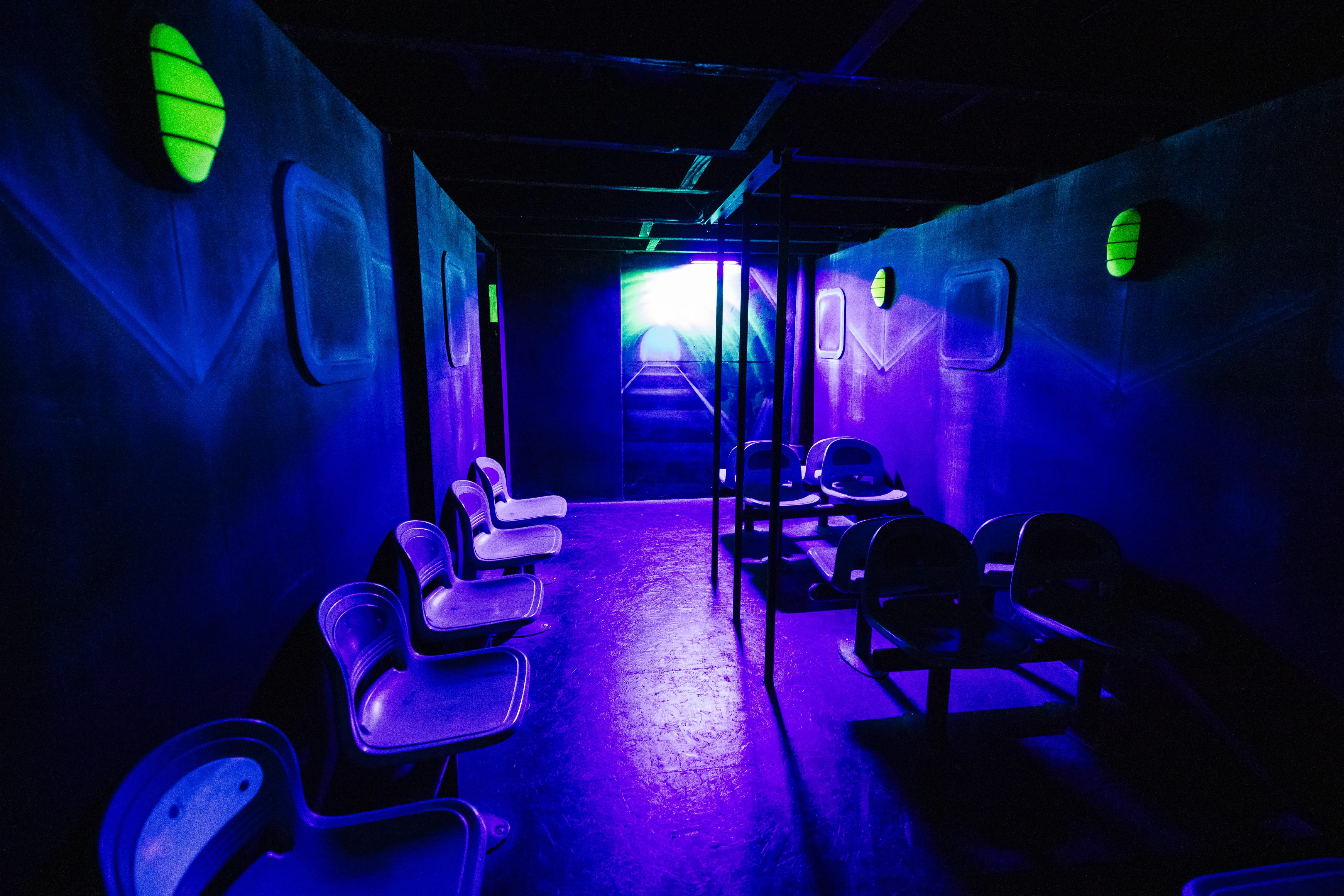 Espace d'attente aux sièges blancs éclairé en bleu, avant l'entrée en arène