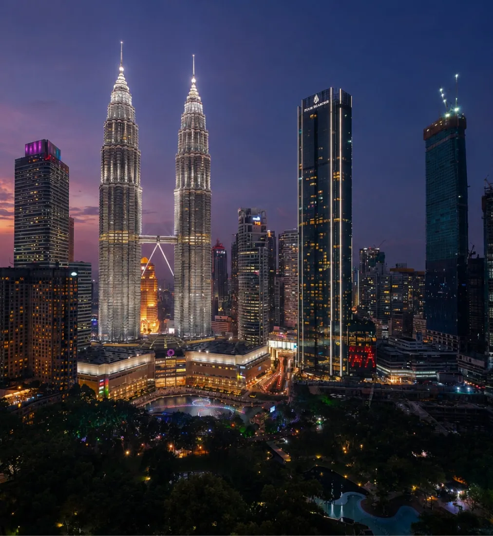 The Petronas Twin Towers lit at dusk above the Kuala Lumpur skyline and KLCC park