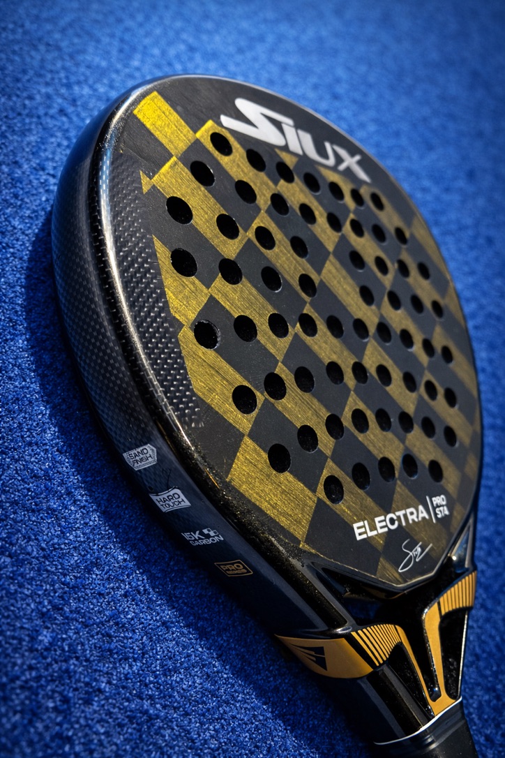 Close-up van een zwart-gouden Siux Electra padelracket op een blauwe padelbaan