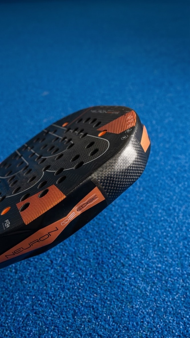 Close-up van een zwart padelracket met koperkleurige accenten en Neuron Edge-opdruk op de padelbaan