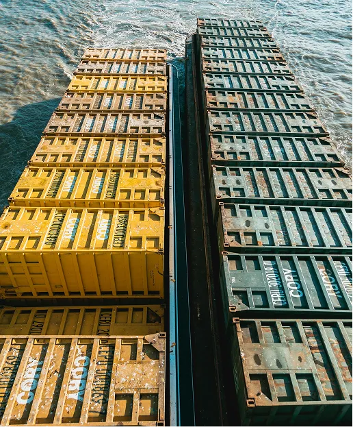 Two rows of large metal shipping containers, one yellow and one dark green, on a ship at sea.