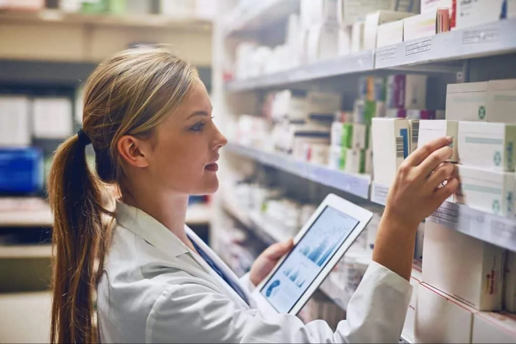 Shot of a pharmacist using her digital tablet while working in an aisle.