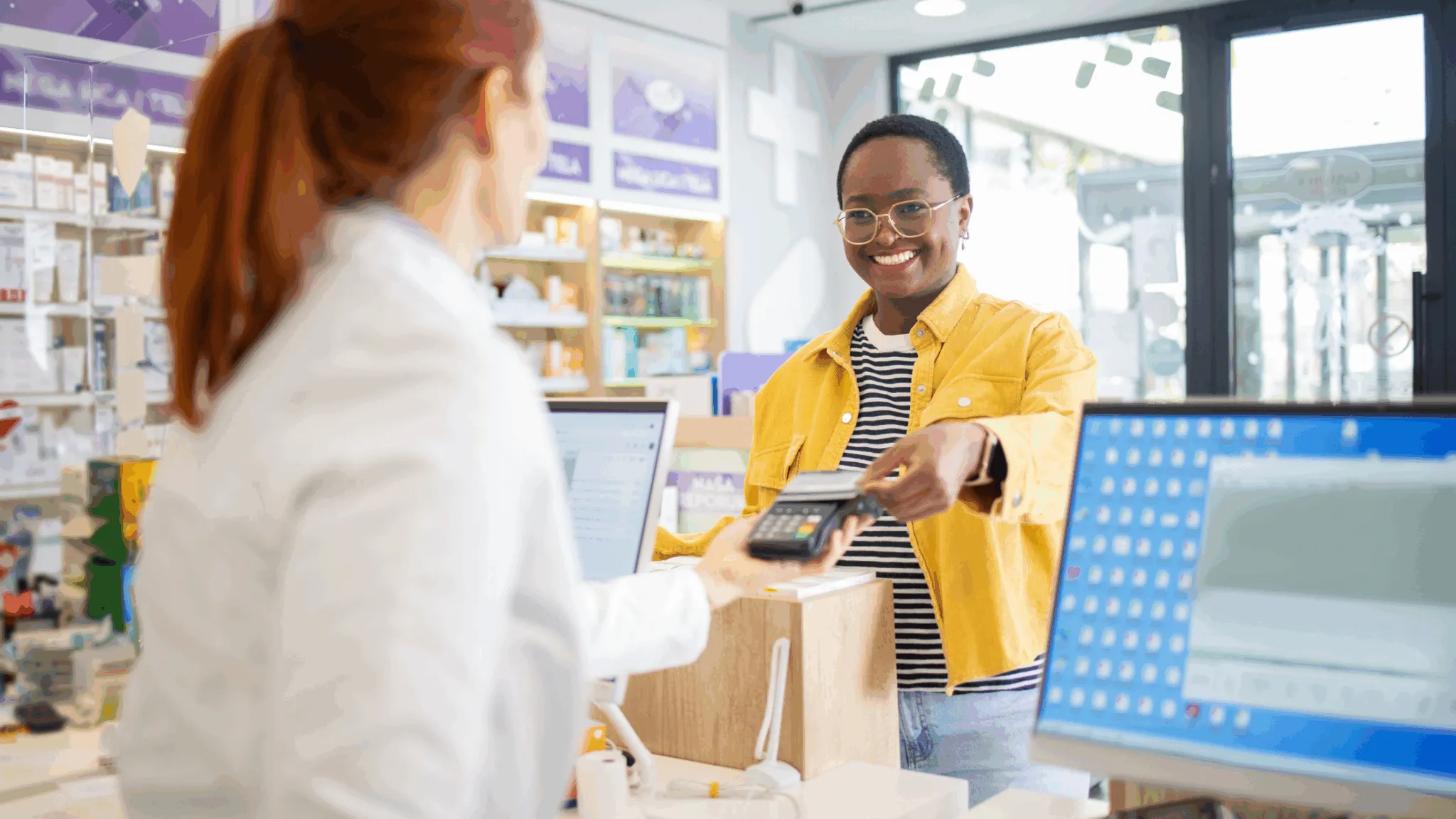 A customer is paying with a card at the pharmacy checkout counter.