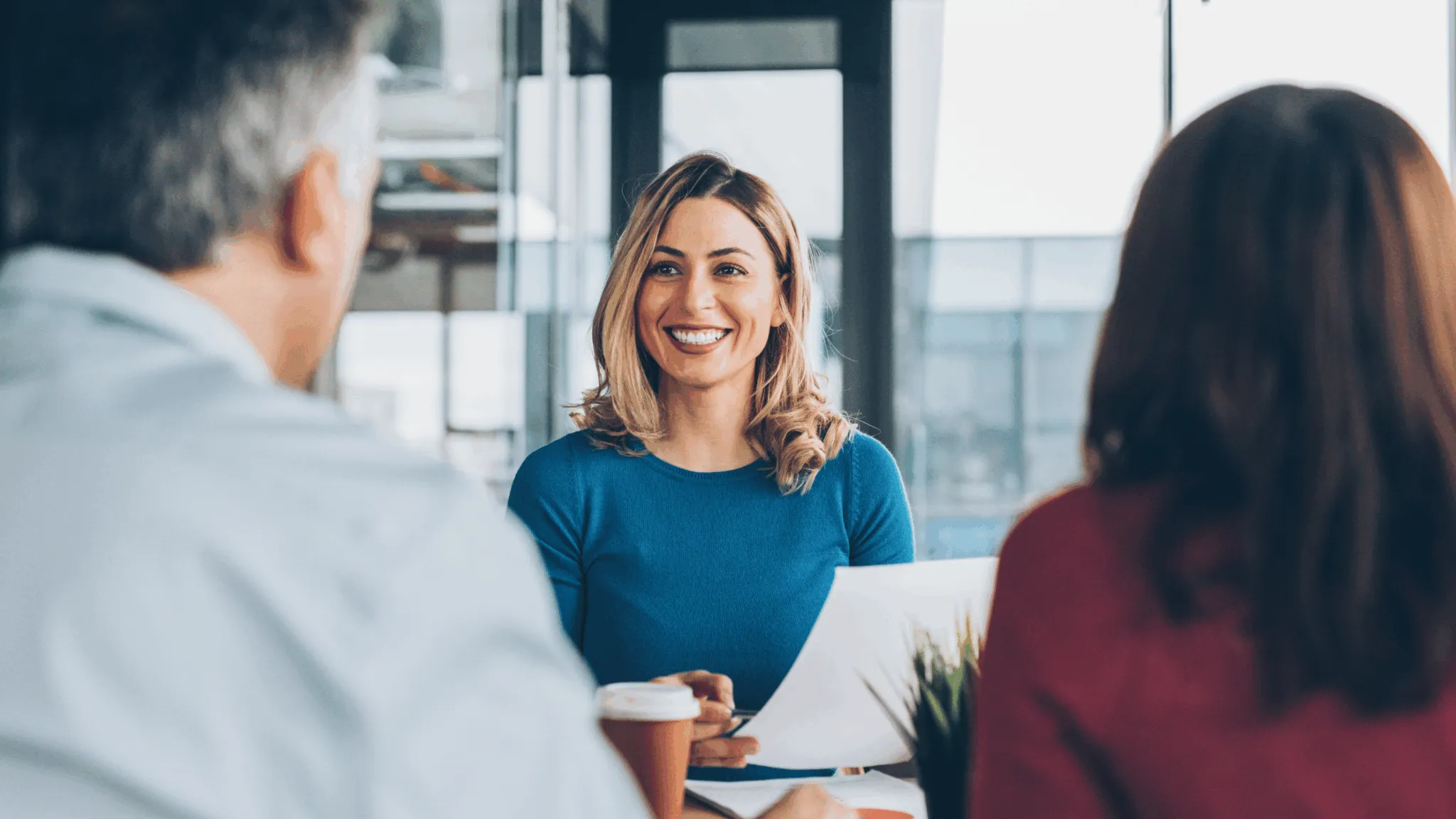 A woman smiling during a professional meeting with colleagues.