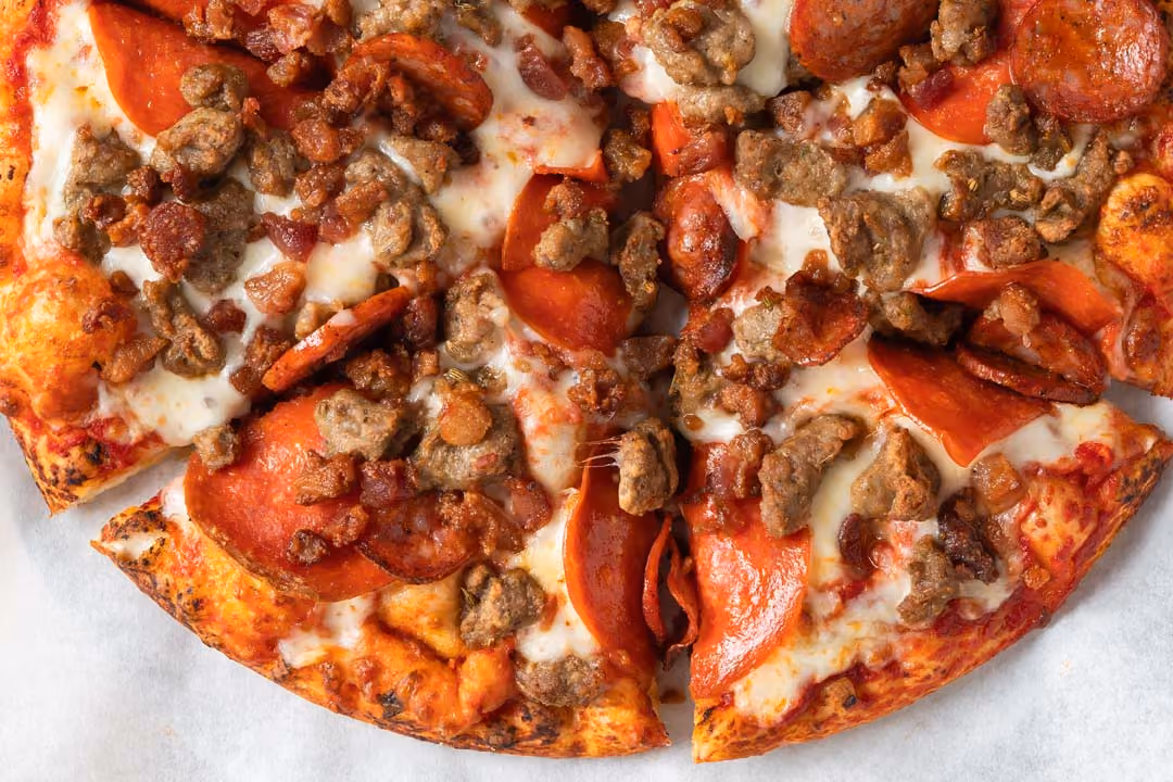 Meat lover's pizza with pepperoni, sausage, bacon, and melted cheese on a golden crust.