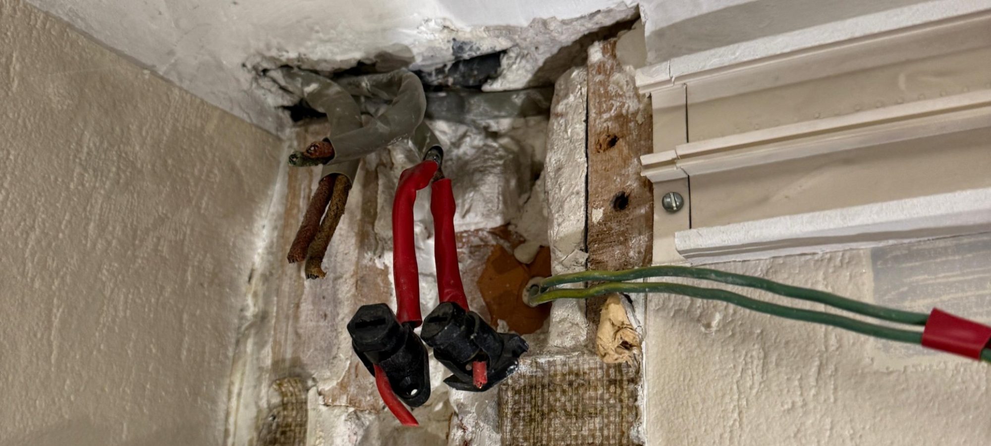 Fils électriques en coton et dominos apparents dans une saignée murale d'un appartement ancien à Lyon