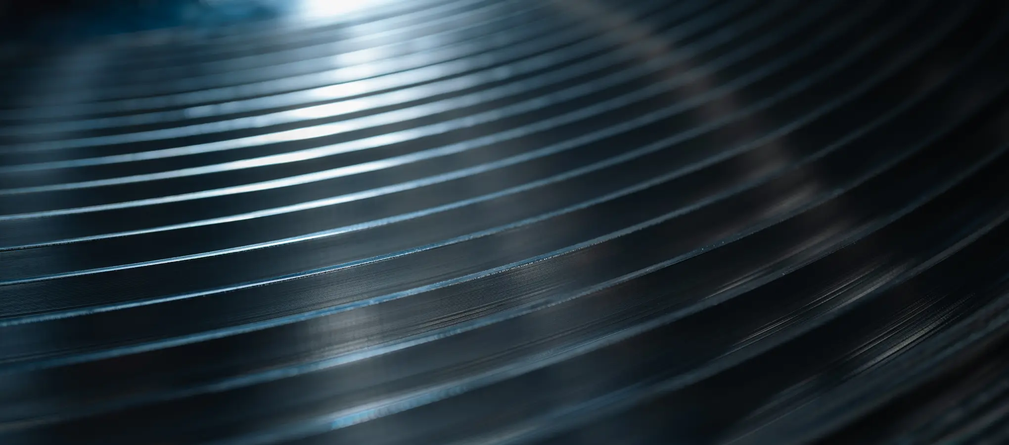 Nahaufnahme einer dunkelblauen Metalloberfläche mit feinen, parallel verlaufenden Rillen.
