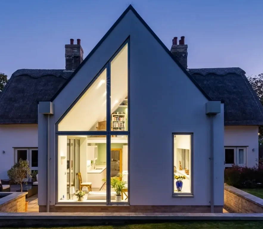House with a large glazed gable lit up at dusk