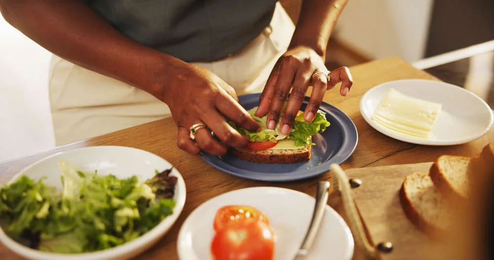 Hands making a wholegrain sandwich with salad and tomato