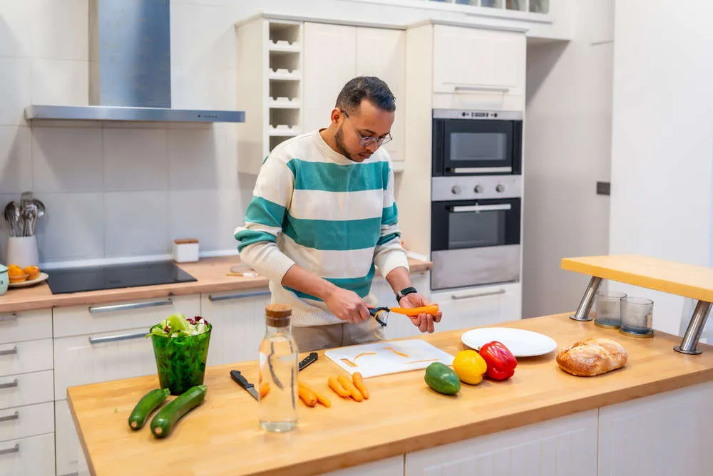 Man chopping carrots in his kitchen while following a nutrition plan